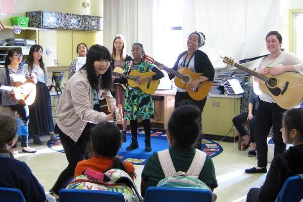 Music therapy students playing guitars for school kids